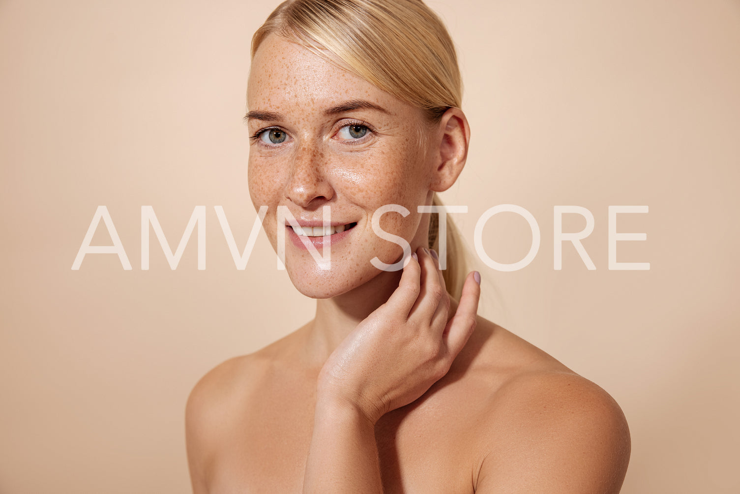 Blond woman looking at camera touching her neck