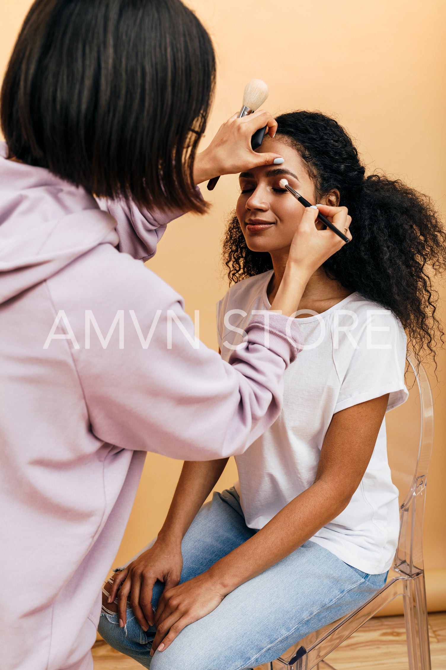 Makeup artist applying eye make up on model in studio	
