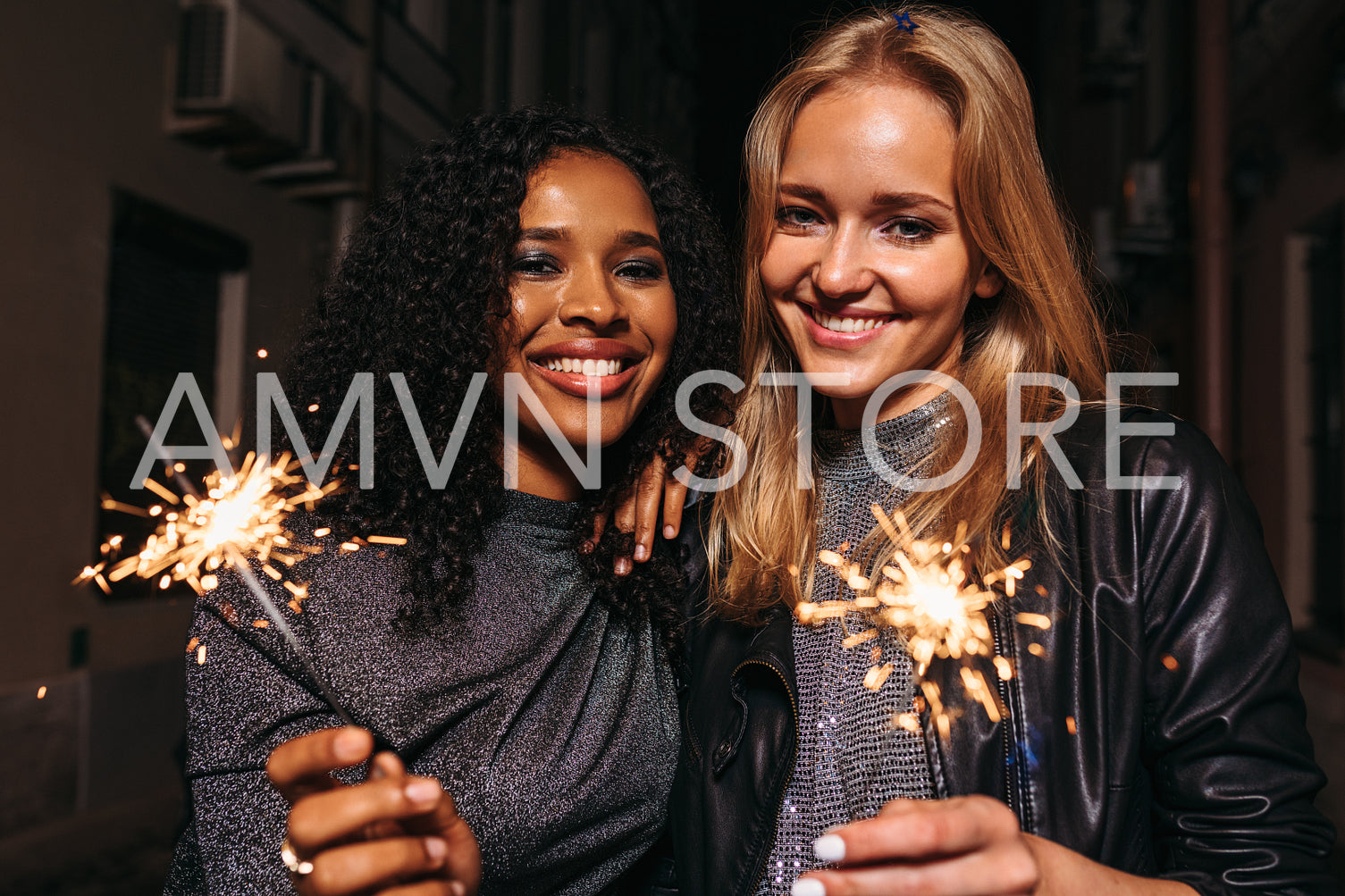 Smiling girls with sparklers looking at camera, standing together	