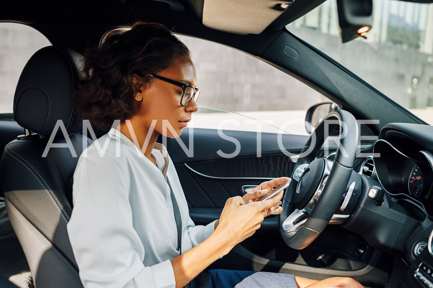 Side view of young businesswoman holding a cell phone in car	