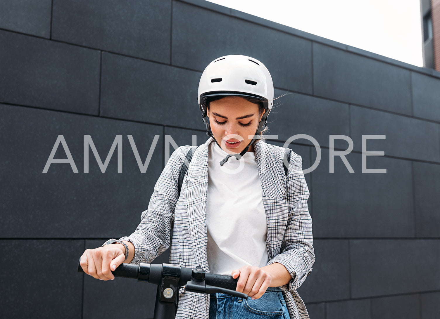 Young caucasian woman wearing white cycling helmet holding handlebar of electric scooter