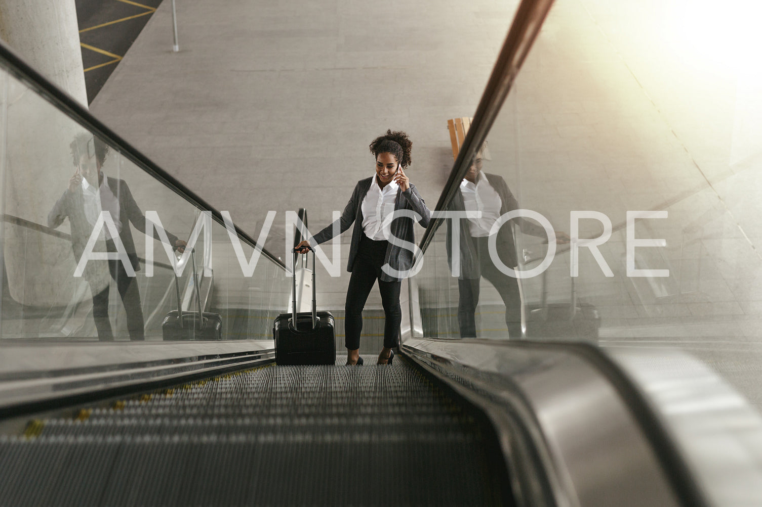 Businesswoman using escalator at airport terminal and holding smartphone	