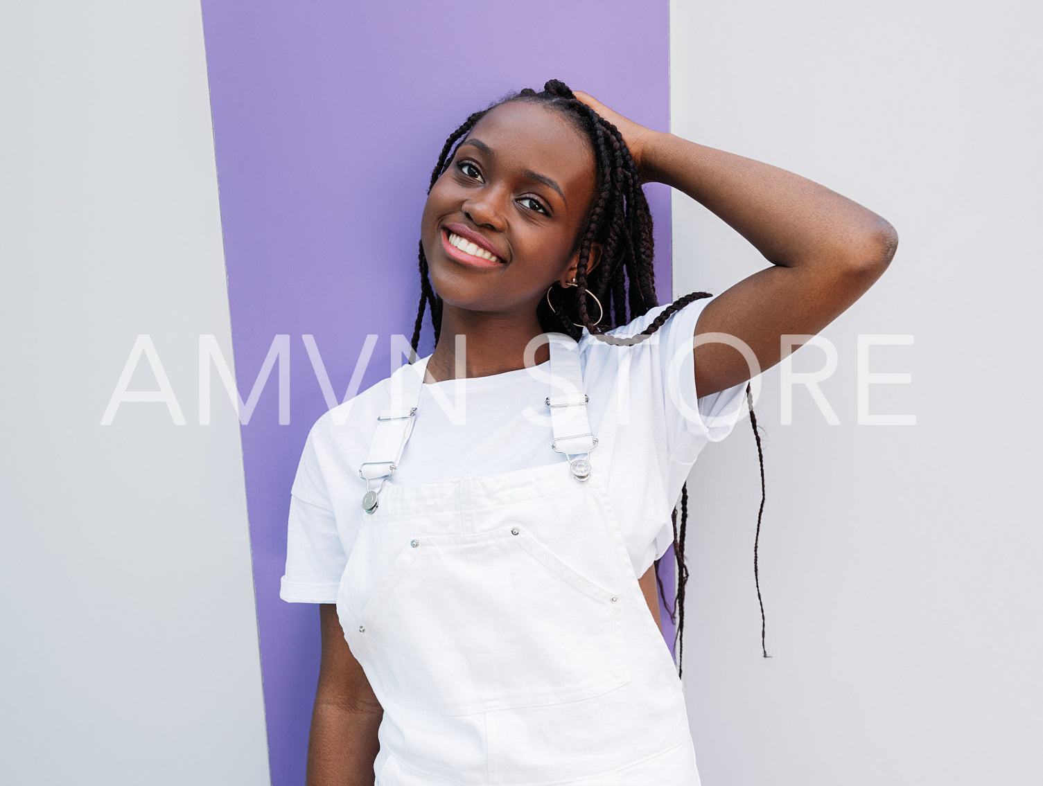 Smiling female adjusting her long braids and looking away 