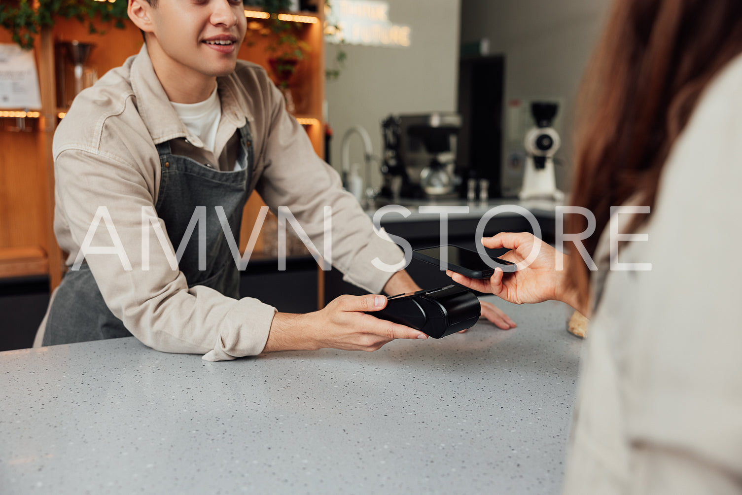 Cropped of a male bartender holding a card machine while customer paying by mobile phone