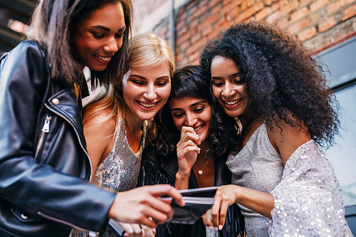 Four smiling women choosing instant photographs outdoors