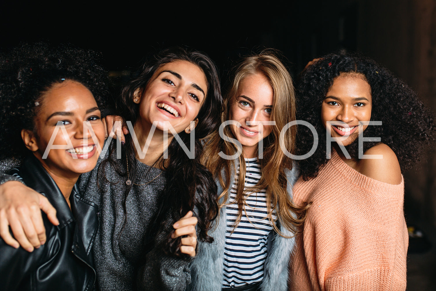 Four beautiful women looking at camera, standing outdoors at night	