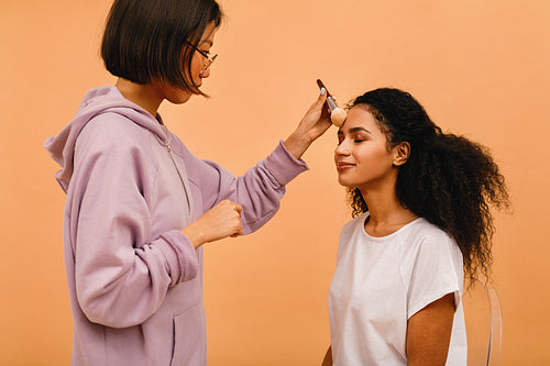 Professional make up artist applying tonal powder on model in studio