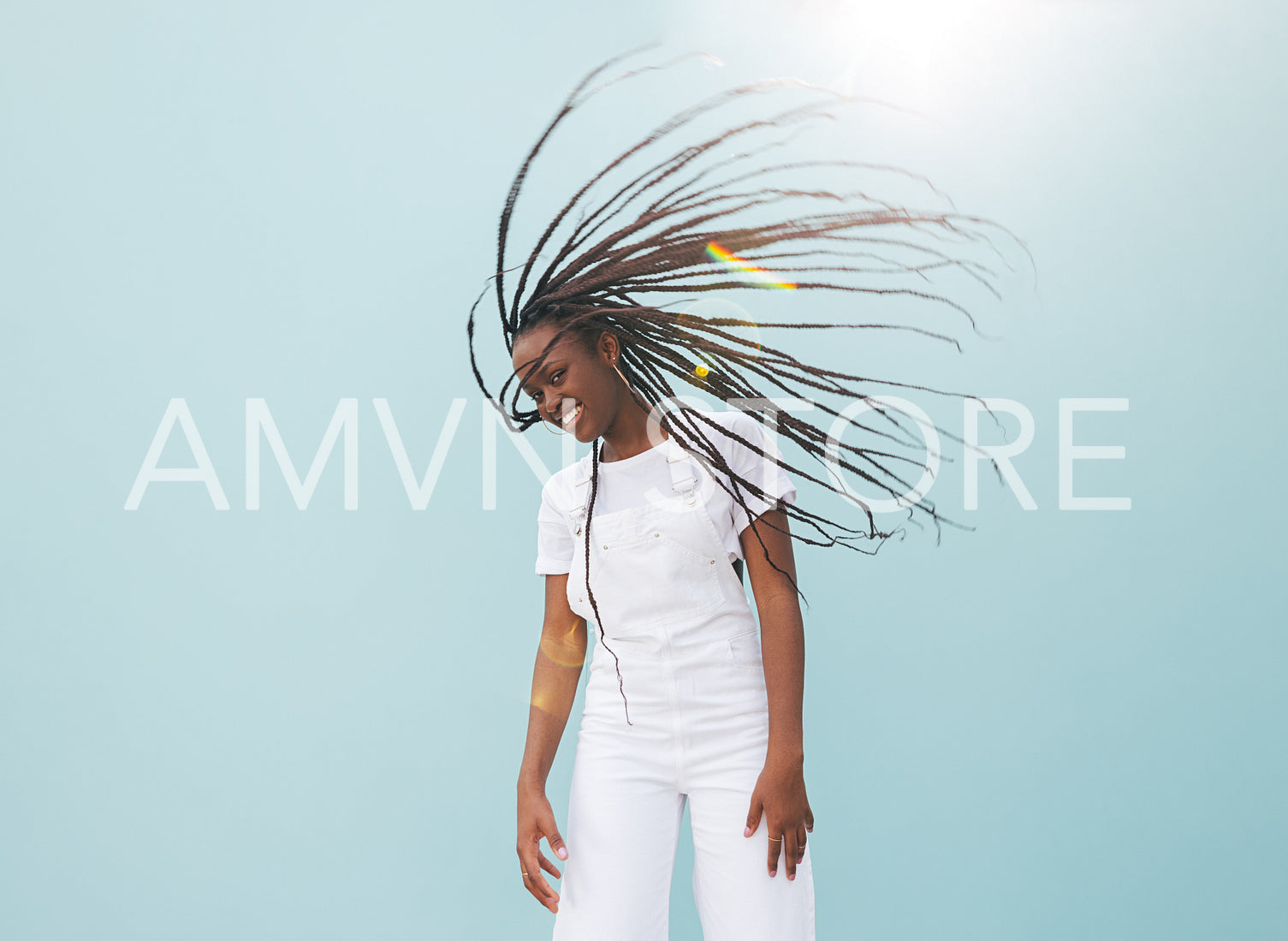 Happy young woman with long braids having fun against blue wall