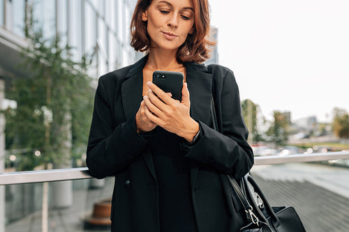 Close-up of a middle-aged businesswoman in formal clothes using a mobile phone