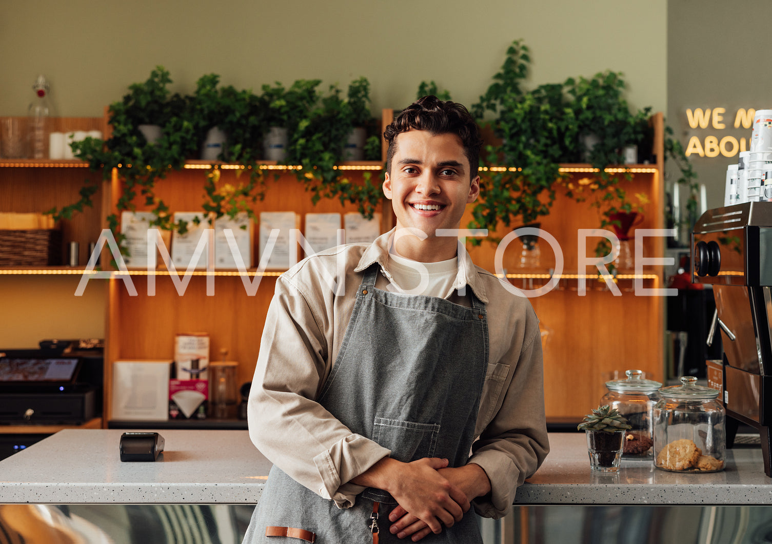 Smiling male waiter in an apron. Portrait of a handsome barista at the counter.