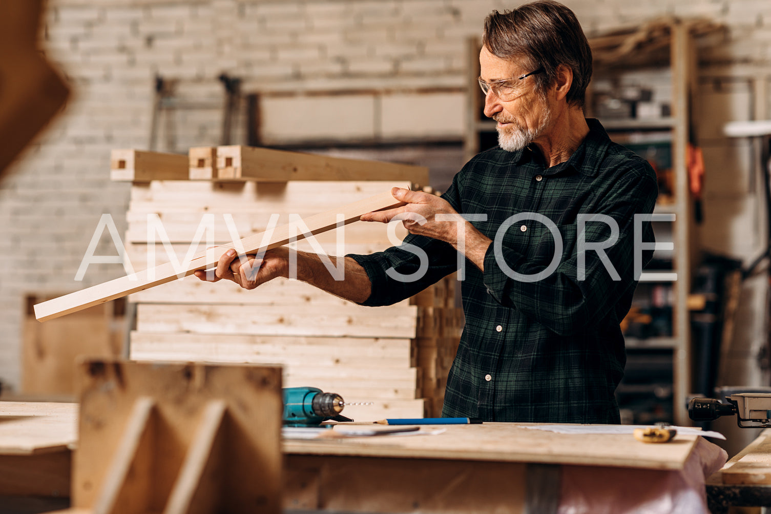 Male carpenter checking straightness of a wooden plank in workshop	