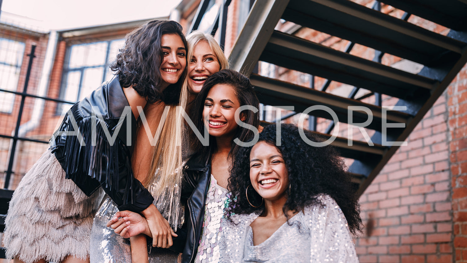 Multi-ethnic group of female friends laughing outdoors standing on the staircase	