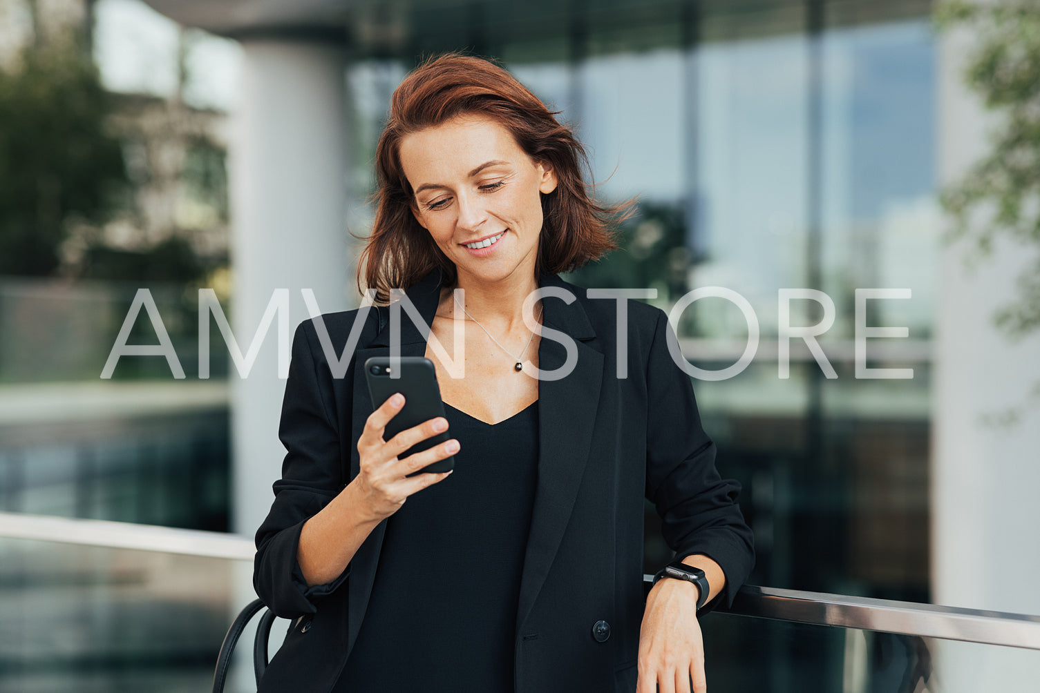 Smiling woman with ginger hair wearing formal wear looking at her smartphone