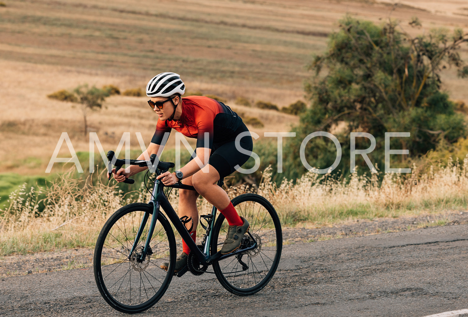 Woman riding a bicycle on empty road. Sportswoman in fitnesswear practicing on pro bike.