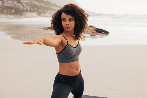 Woman in sportswear stretching her arms on a beach