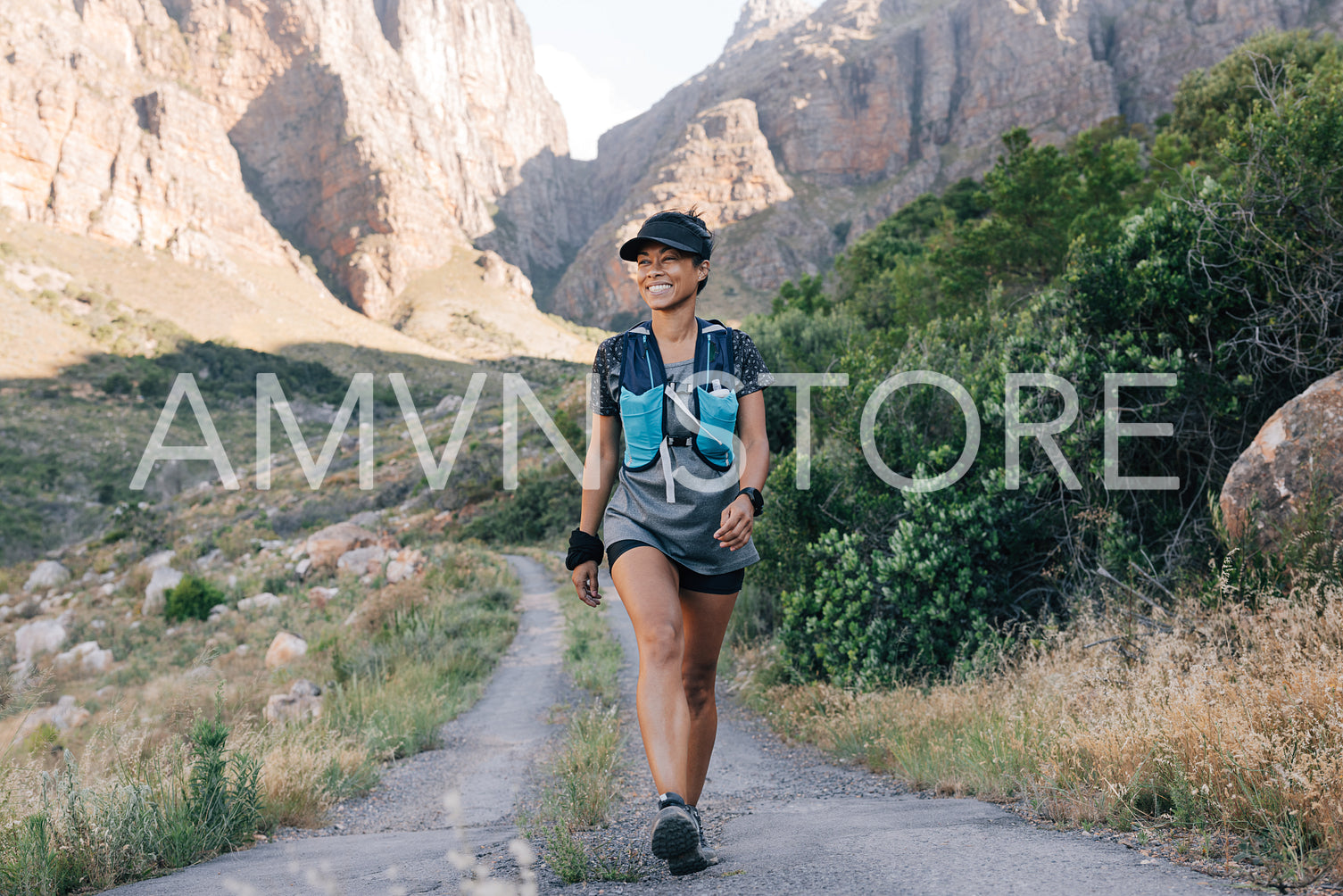 Woman walking on a country road. Young smiling female hiking in nature.