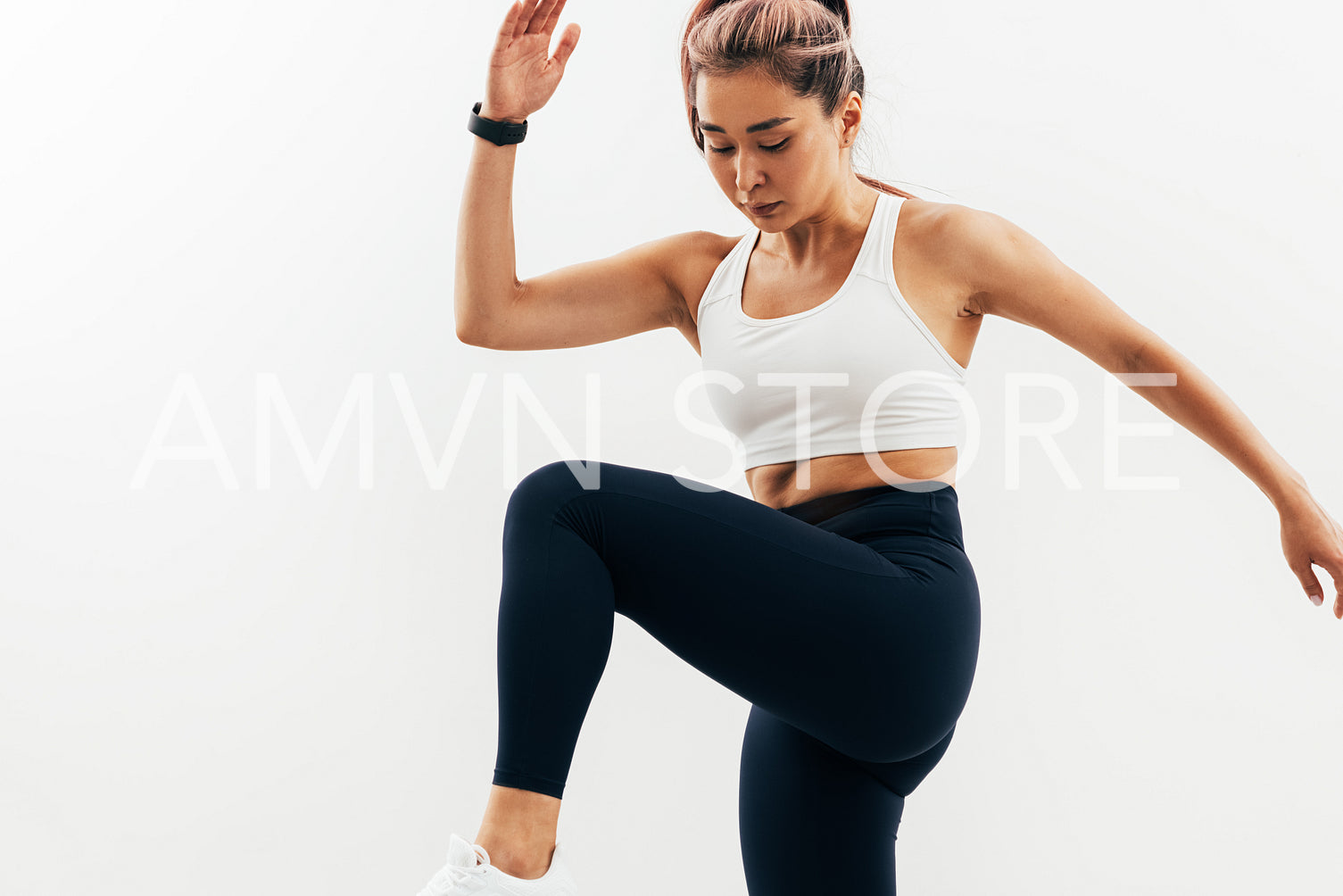 Young Asian woman doing warming up exercises against white wall