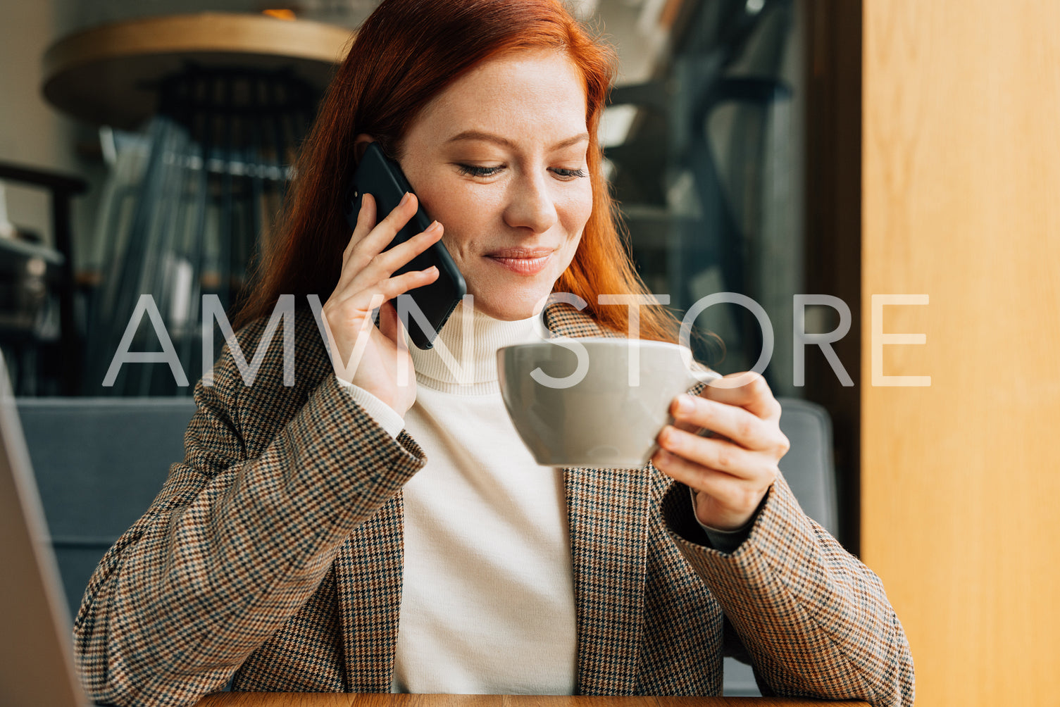 Redhead woman talking on mobile phone while drinking coffee