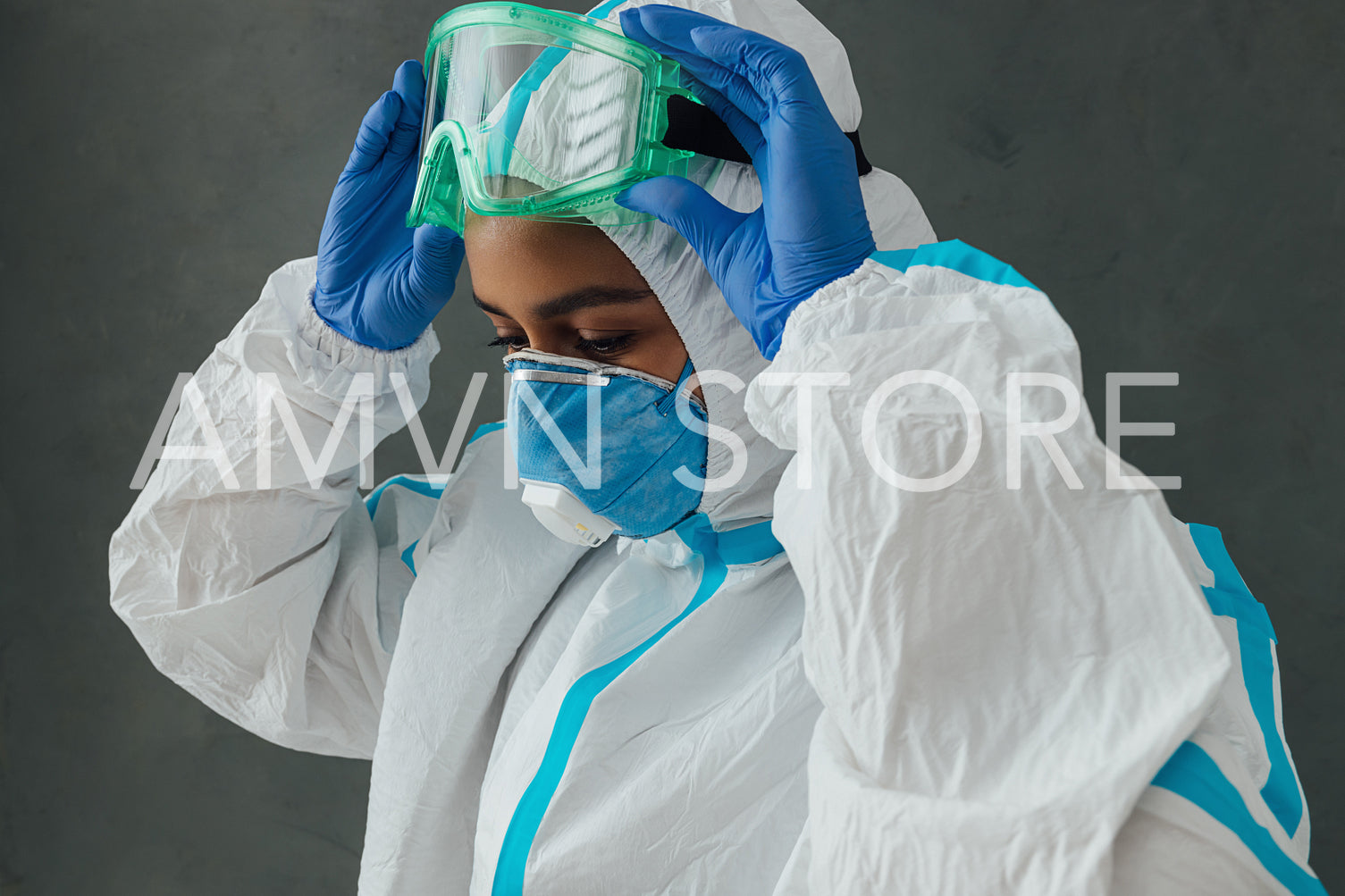 Female medical specialist putting on protective glasses. Doctor in protective suit preparing for work during a pandemic.	