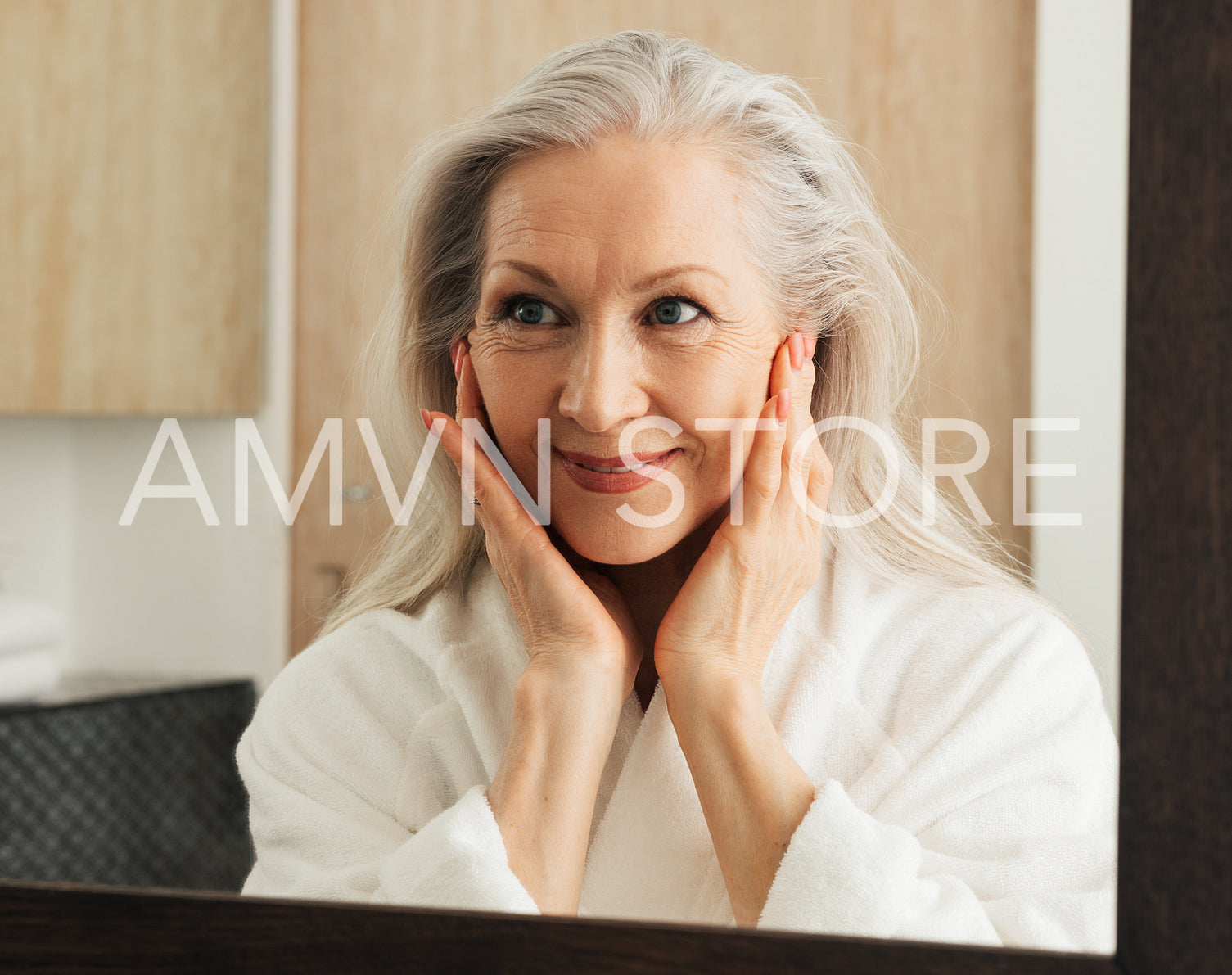 Portrait of a smiling mature woman with grey hair looking at a mirror in bathroom