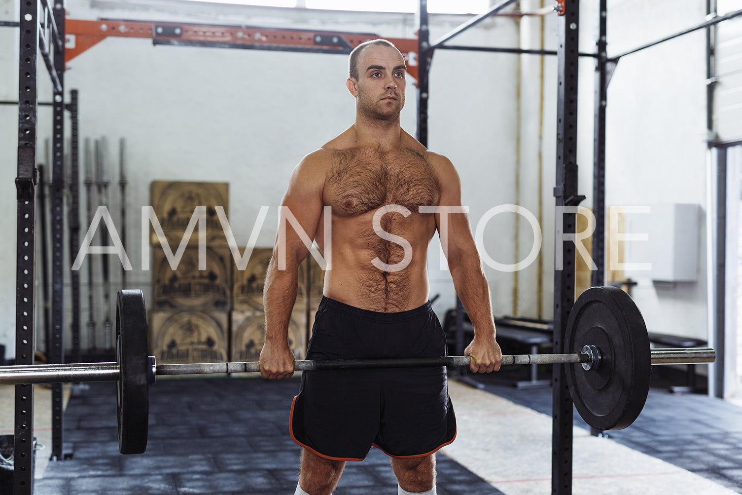 Fit male athlete exercising with heavy weights at training gym.	