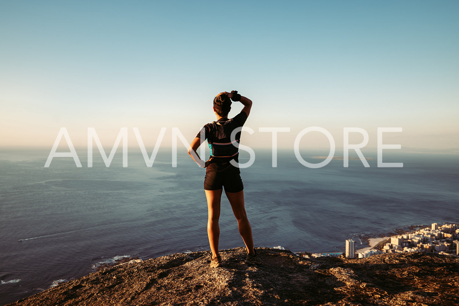 Back view of fit woman standing on cliff