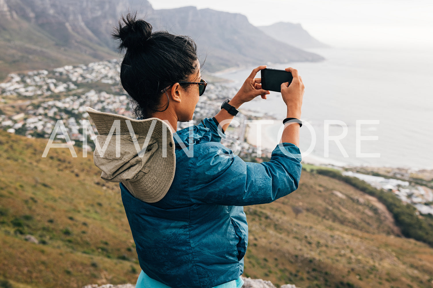 Young woman taking photographs with her smartphone while hiking on a mountain. Female hiker making photos for her social media.