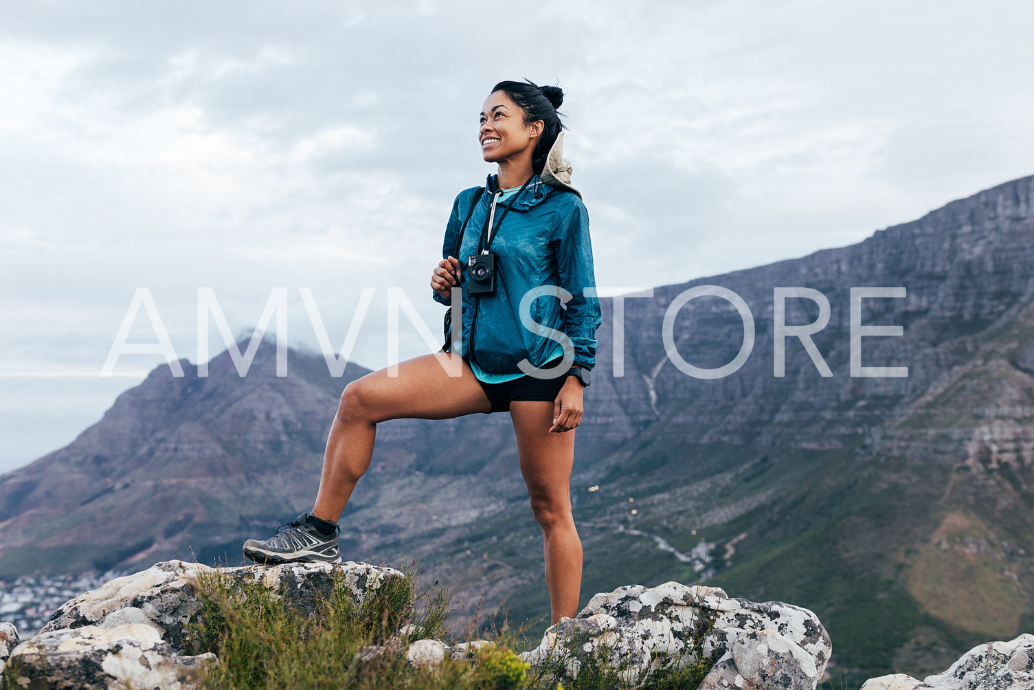 Young woman with backpack standing on the top of a hill. Smiling female enjoying being on the top of the mountain.