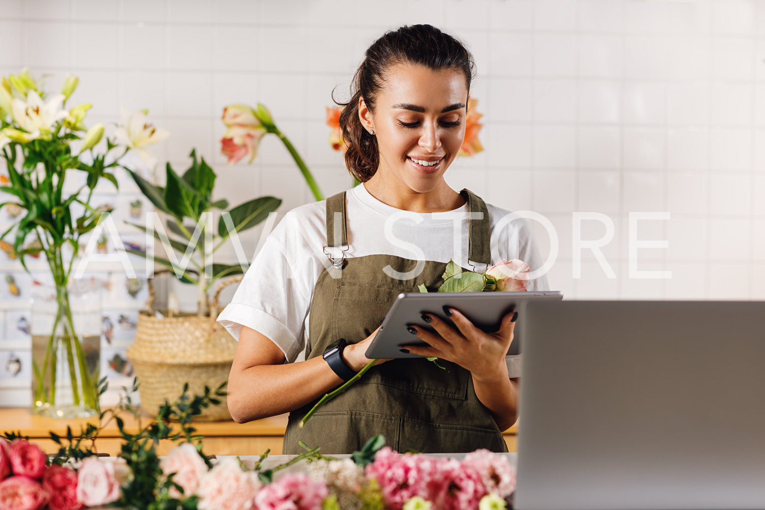 Flower shop owner holding a flower and digital tablet in hands	