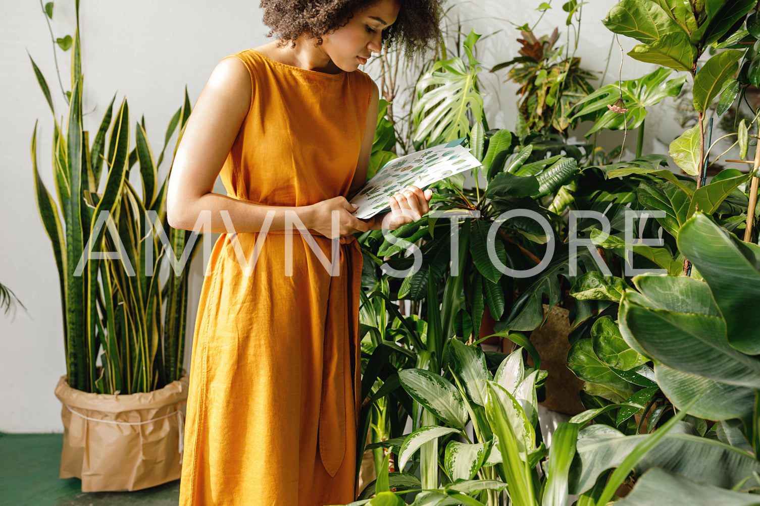 Young woman holding a book and observe a plant in workshop	