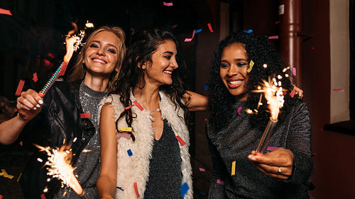 Three happy women walking and hugging on night street