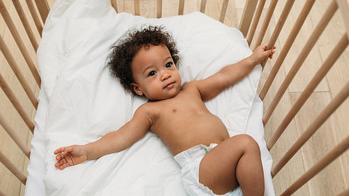 Curly haired baby boy lying in a crib