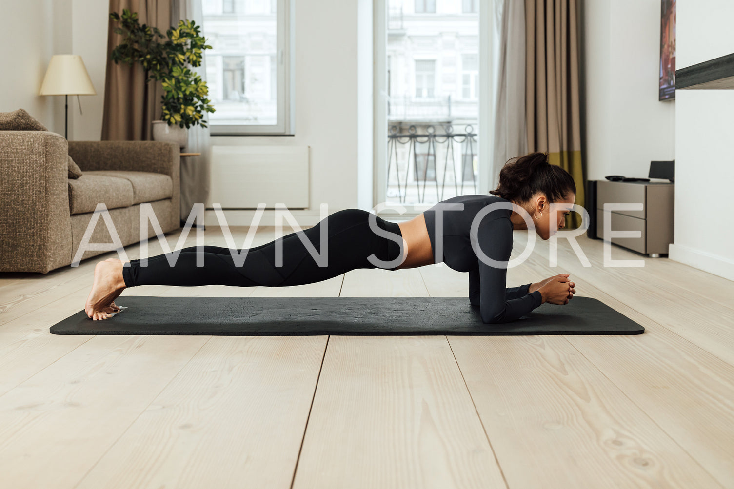 Side view of a slim woman in sportswear doing plank