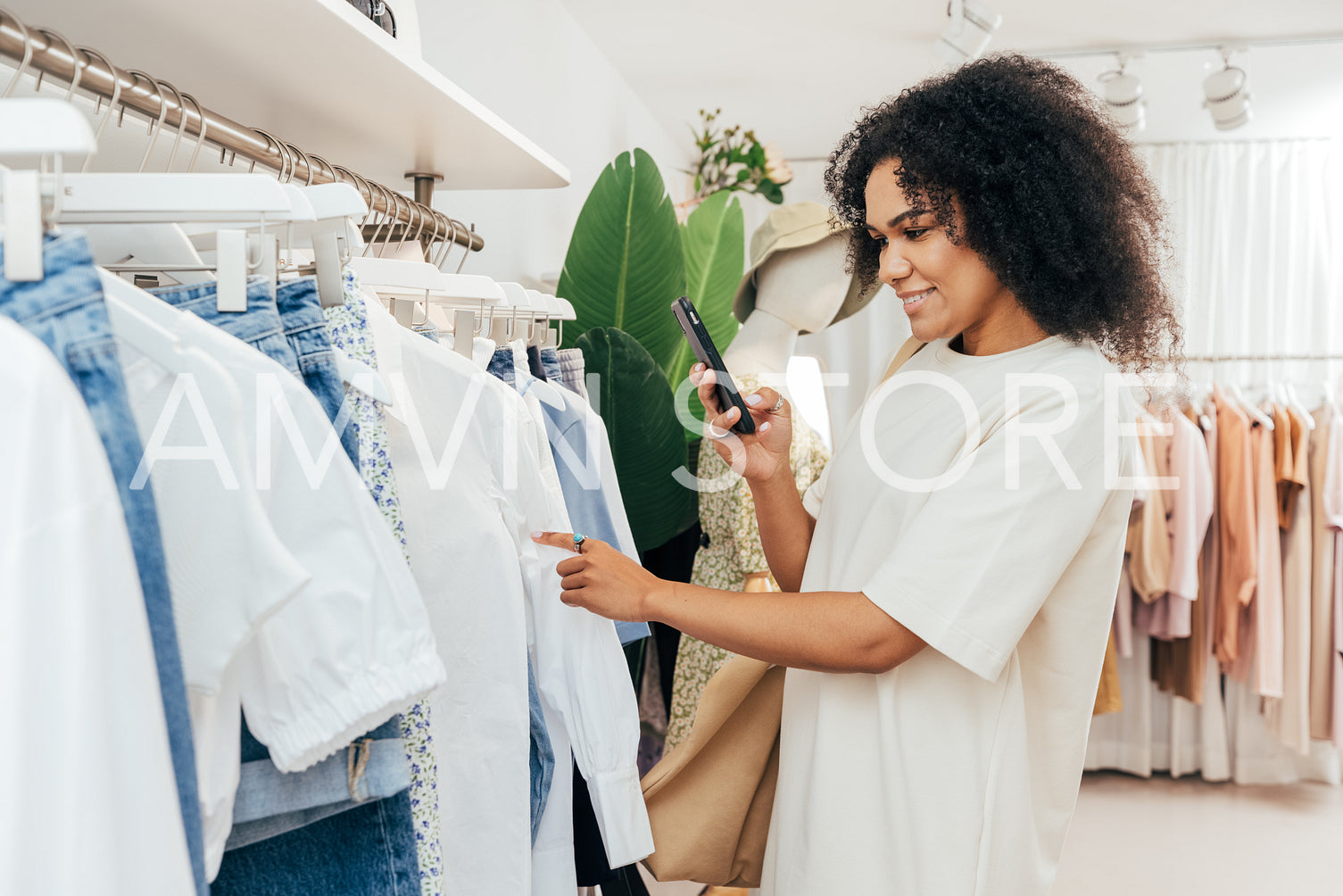 Side view of young woman photographing clothes in shop