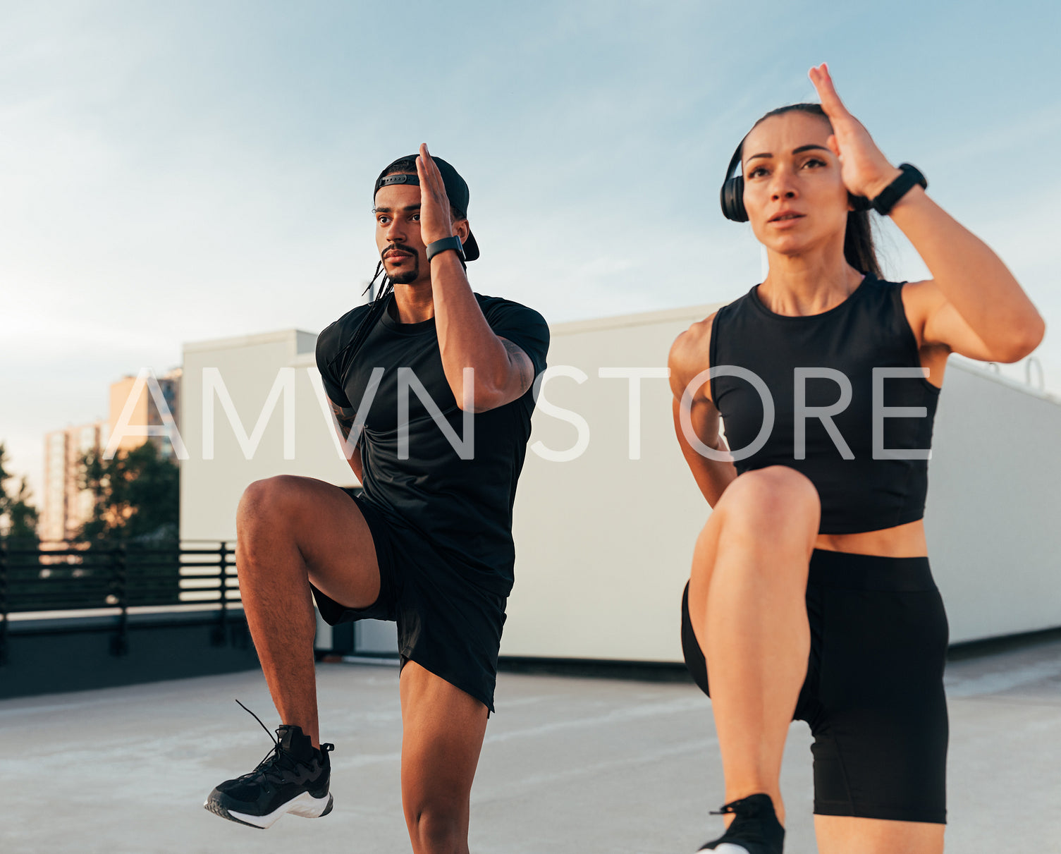 Two athletes in black sportswear practicing together on the roof