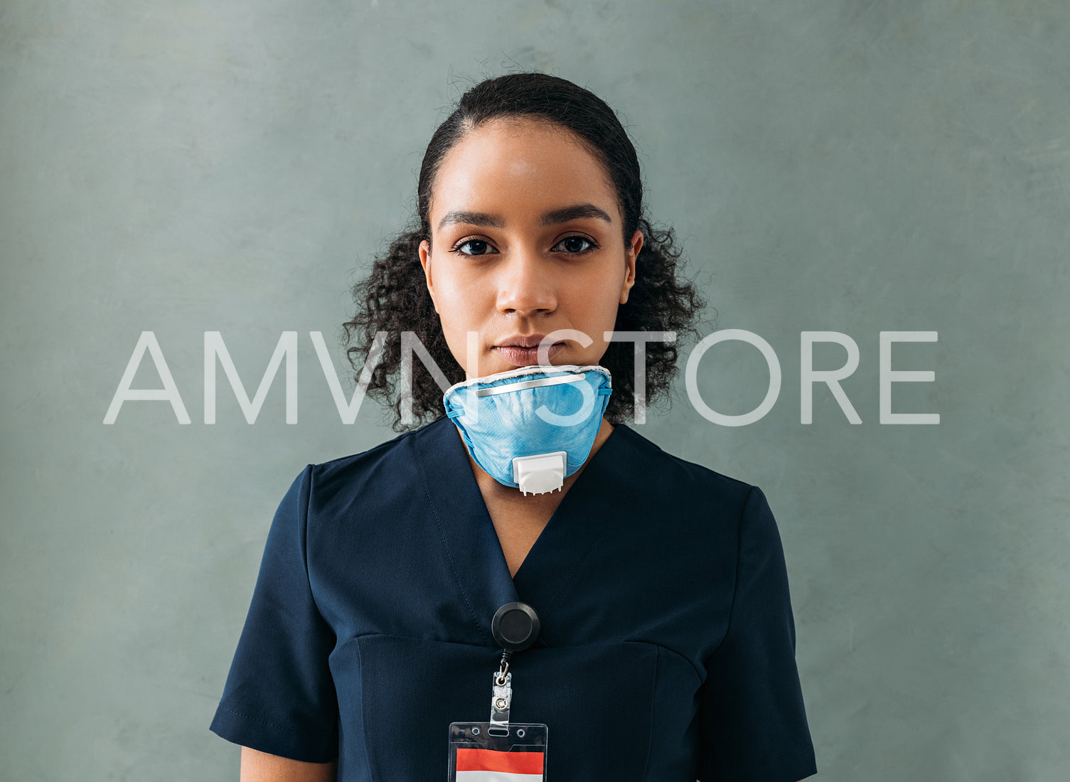 Female doctor with a medical mask under her chin. Woman in uniform standing at wall