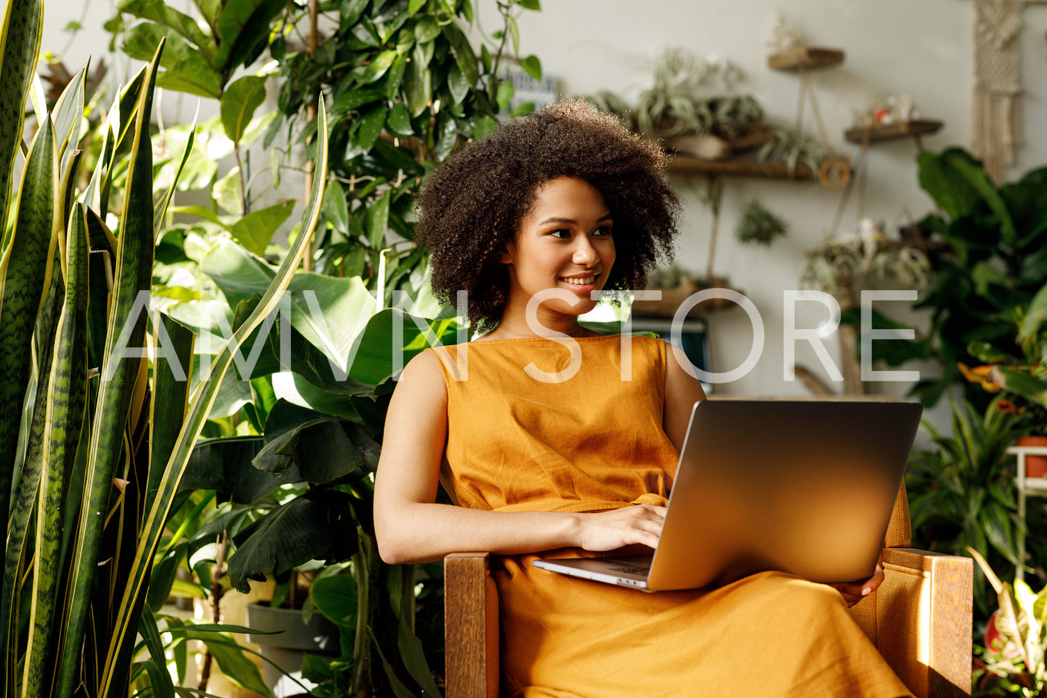 Female botanist typing on laptop in her workshop looking away	