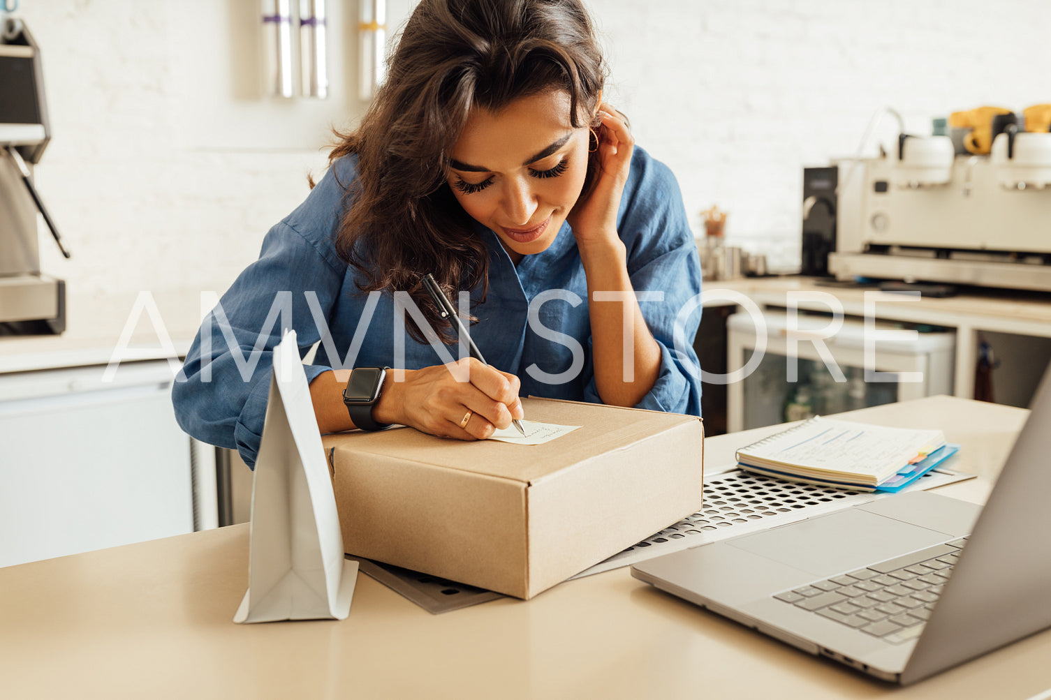 Female business owner working in a coffee shop, makes notes on a cardboard box for delivery	