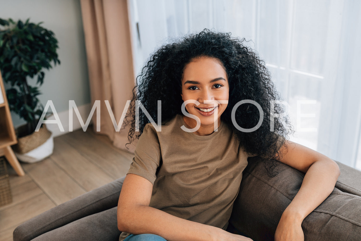 Portrait of a young woman with curly hair sitting on a sofa