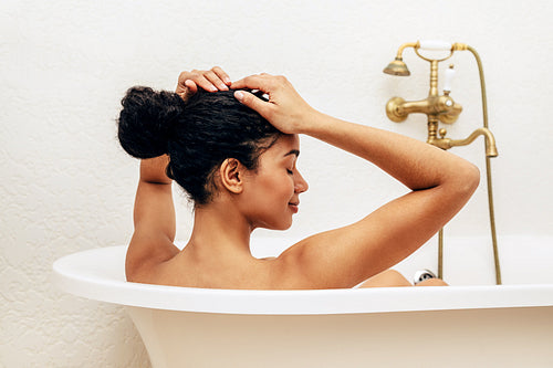 Woman relaxing in bathroom, straightens her hair