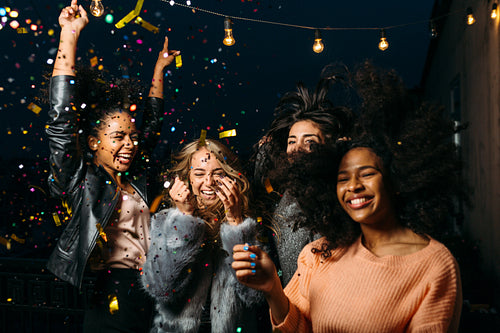 Group of female friends enjoying night party, throwing confetti