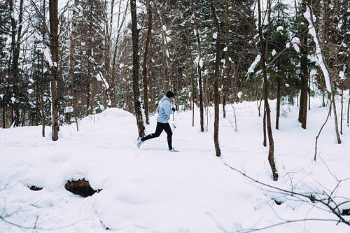 Side view of young sportsman exercising in snow forest