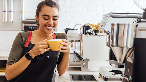 Laughing barista holding a mug. Smiling waitress taking a break in the cafeteria.