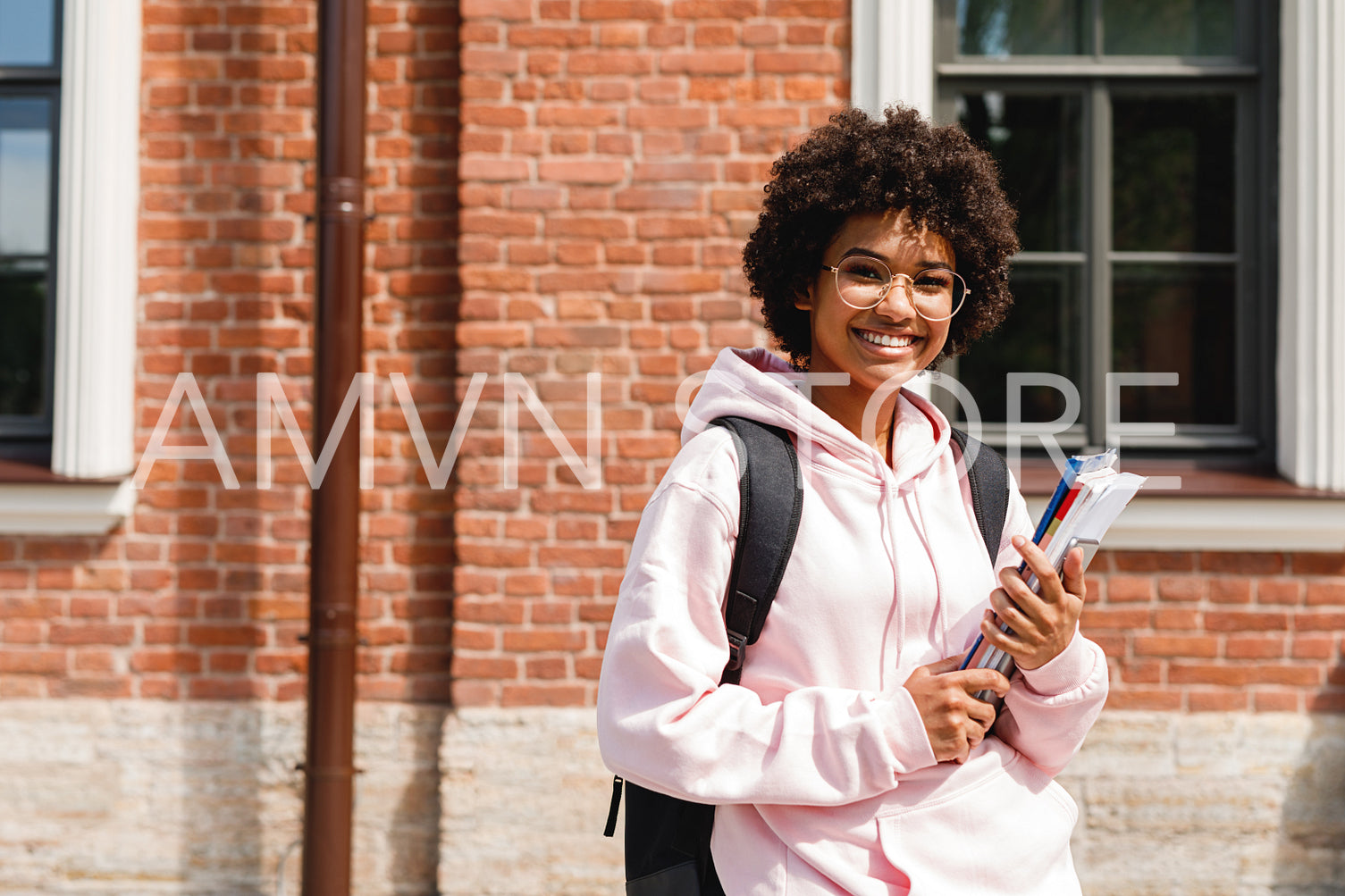 Smiling girl standing at school with books and backpack	