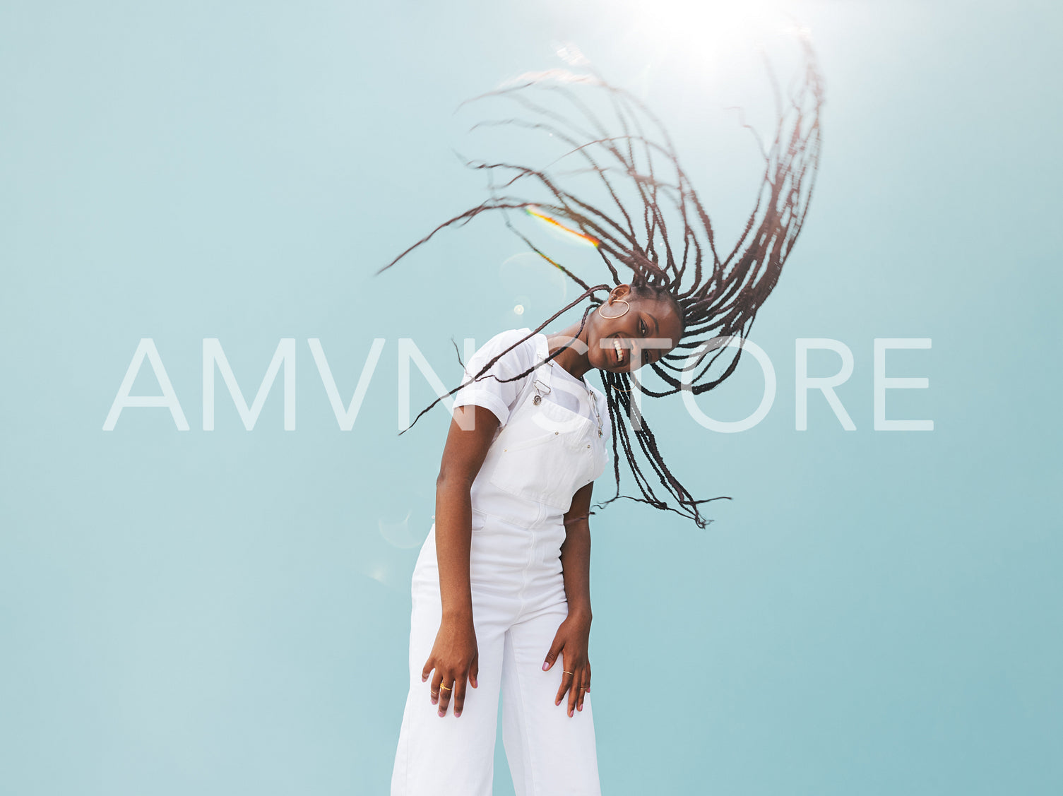 Young female in white casuals with long braids against blue wall