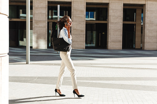 Side view of young businesswoman walking in front of a modern building