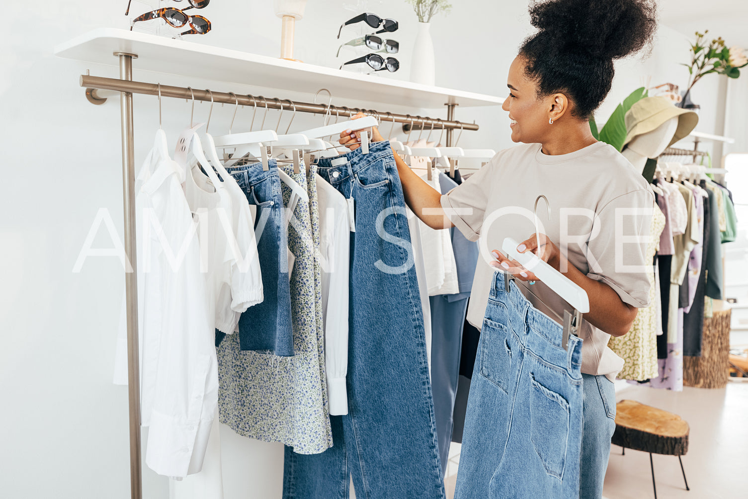 Saleswoman standing in clothing store, arranging clothes on a rail