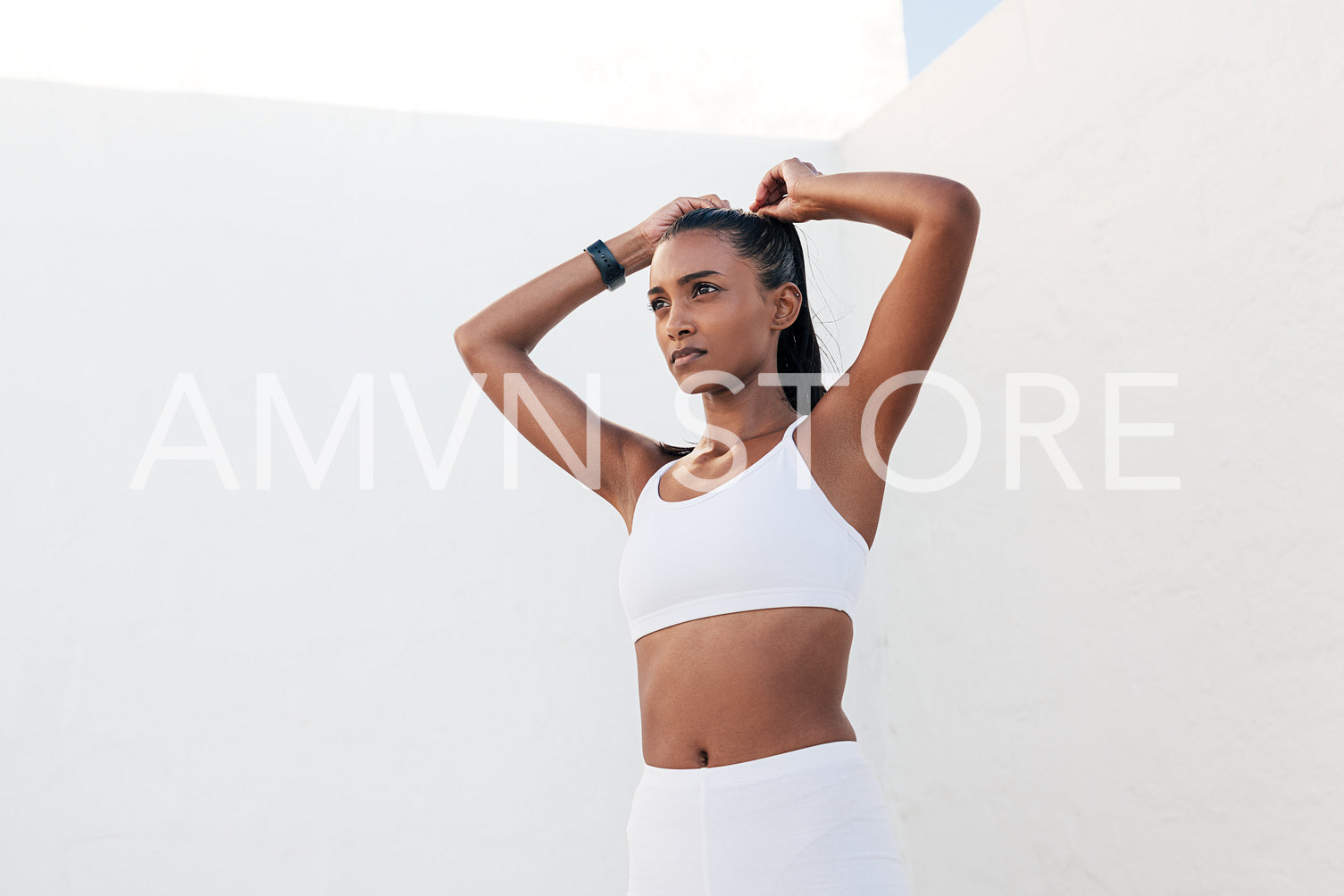 Confident sportswoman adjusting her hair while standing outdoors in a white location