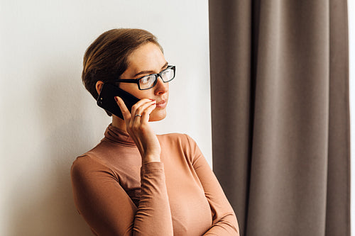 Businesswoman in casual clothes standing in a rental apartment and making phone call