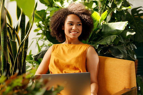 Woman florist sitting at her workshop with laptop and looking away